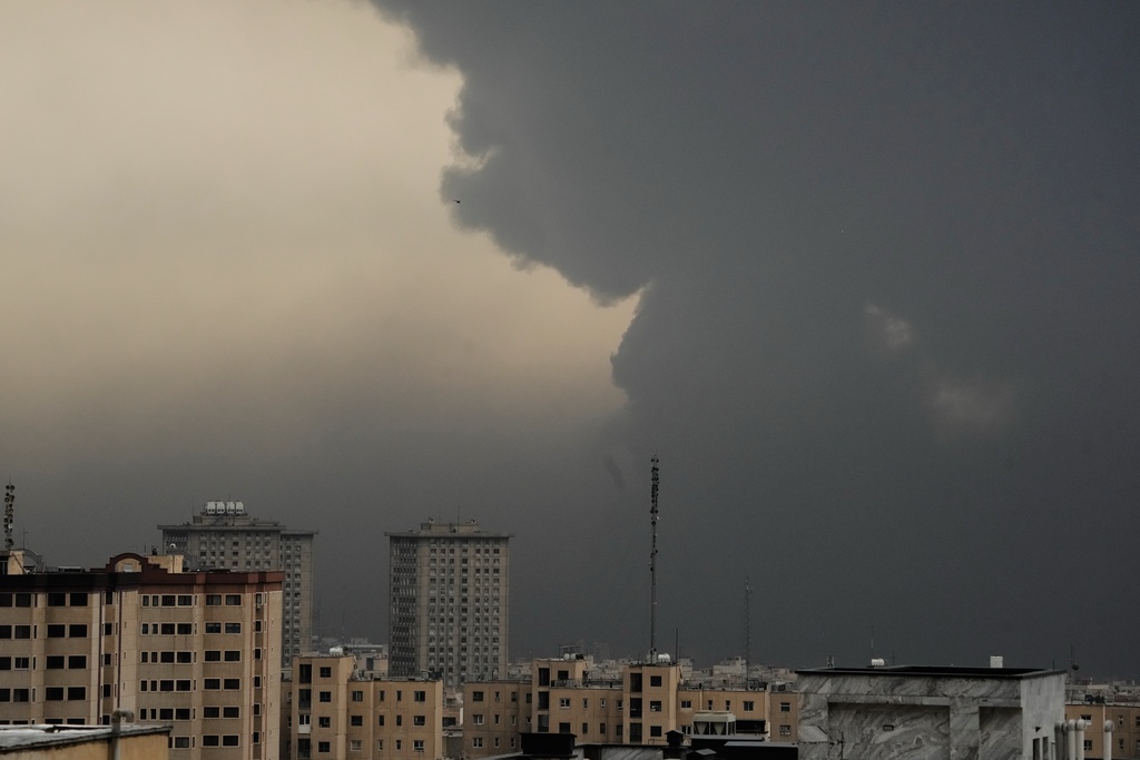 Plumes of smoke from a U.S.-Israeli strike on an oil facility late Saturday linger in the cloudy sky over Tehran, Iran, Sunday, March 8, 2026. (AP Photo/Vahid Salemi)