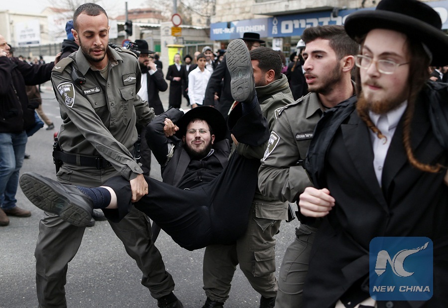 TOPSHOT - Israeli policemen arrest ultra-Orthodox Jews during a protest against Israeli army conscription, in an ultra-Orthodox Jewish neighbourhood of Jerusalem, on February 9, 2017. Many ultra-Orthodox oppose military service for their young men because they believe it exposes them to influences and temptations not found in the insular world of prayer and religious study.  / AFP PHOTO / AHMAD GHARABLI / ALTERNATIVE CROP
